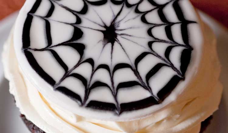Spooky cupcake with spider web frosting design.