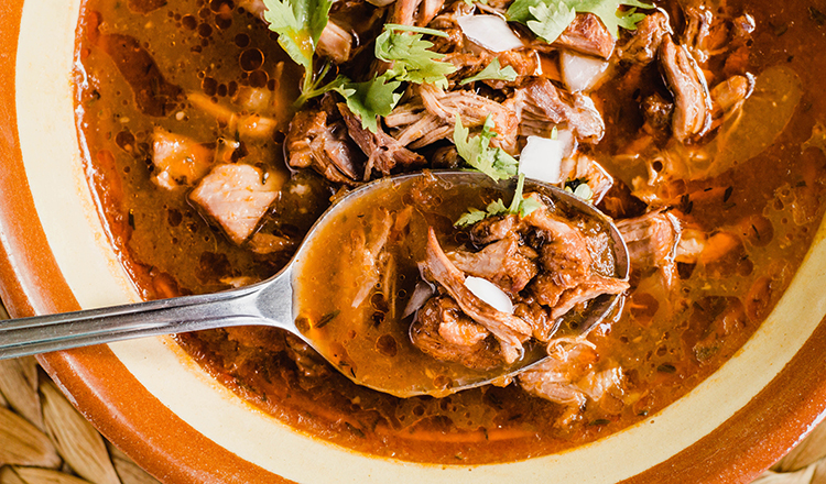 Traditional birria de res, a Jalisco style beef soup typical from Mexico. Close-up of the stew with a spoon