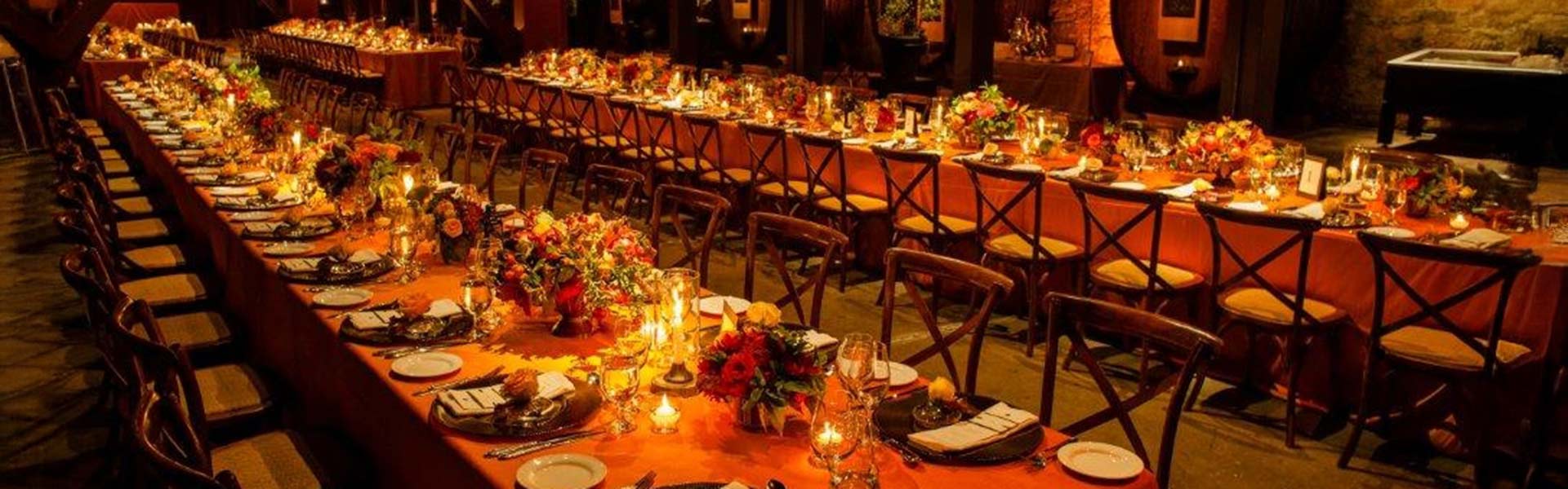 Banquet tables set for a CIA at Greystone dining event in a dim wine cellar.