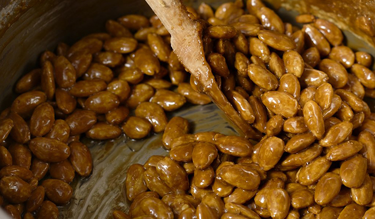 The crystal-coated almonds are heated to toast the nuts, melt the sugar crystals and form a thin layer of caramelized sugar around them.