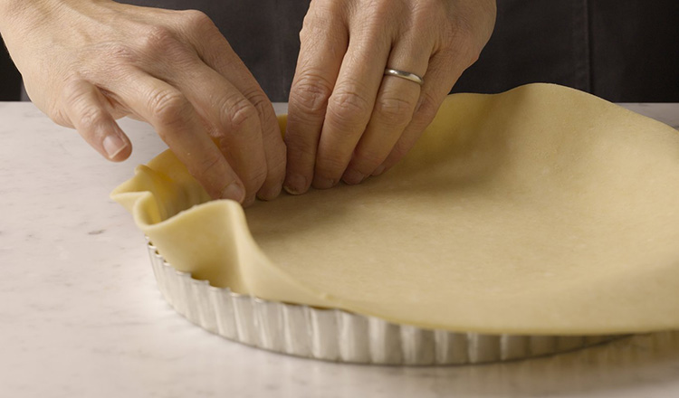 Vanilla tart dough being fitted into a tart pan