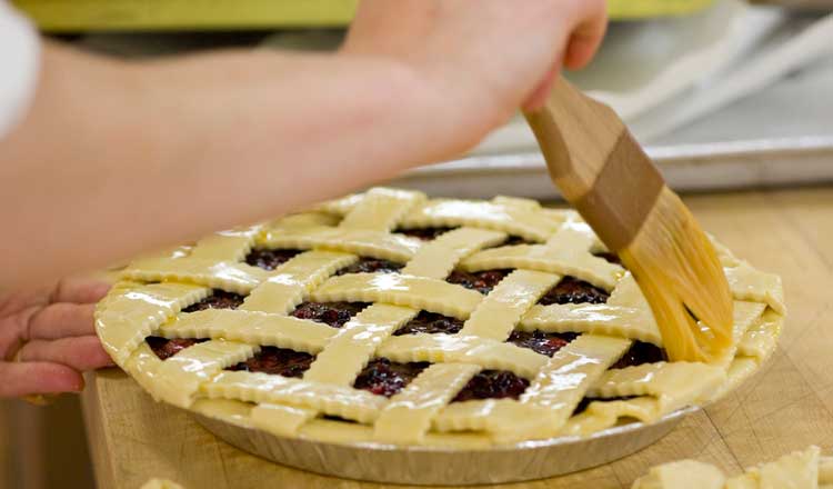 Fruit pie getting an egg wash.