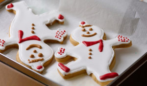 Decorated snowman cookies packaged in a tin container.