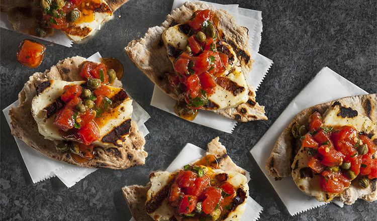 Grilled east mediterranean cheese on a pita bread topped with tomatoes and capers