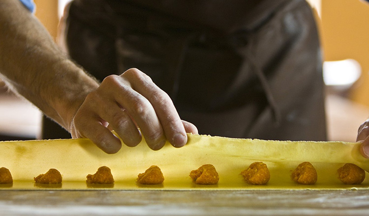 Chef preparing fresh ravioli on counter.