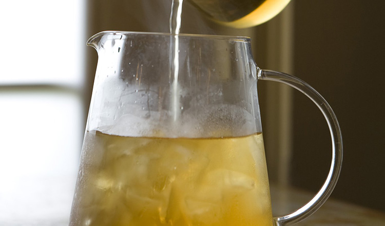 Tea being poured over ice in a pitcher.