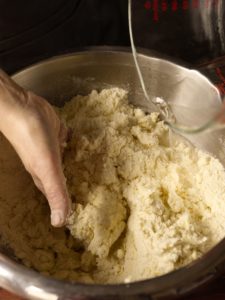 Adding cold water to pie dough mixture.