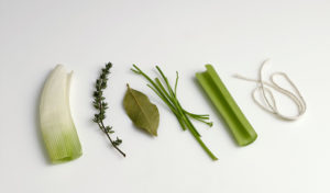 Ingredients for a standard bouquet garni, a small bundle of herbs tied with string and used to flavor stocks, braises, and other preparations. Usually contains bay leaf, parsley, thyme, and possibly other aromatics wrapped in leek leaves.