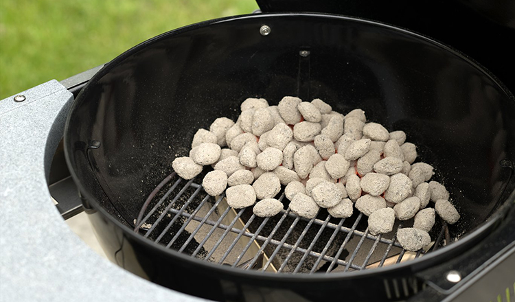 Charcoal arranged on one side of a grill for indirect cooking.