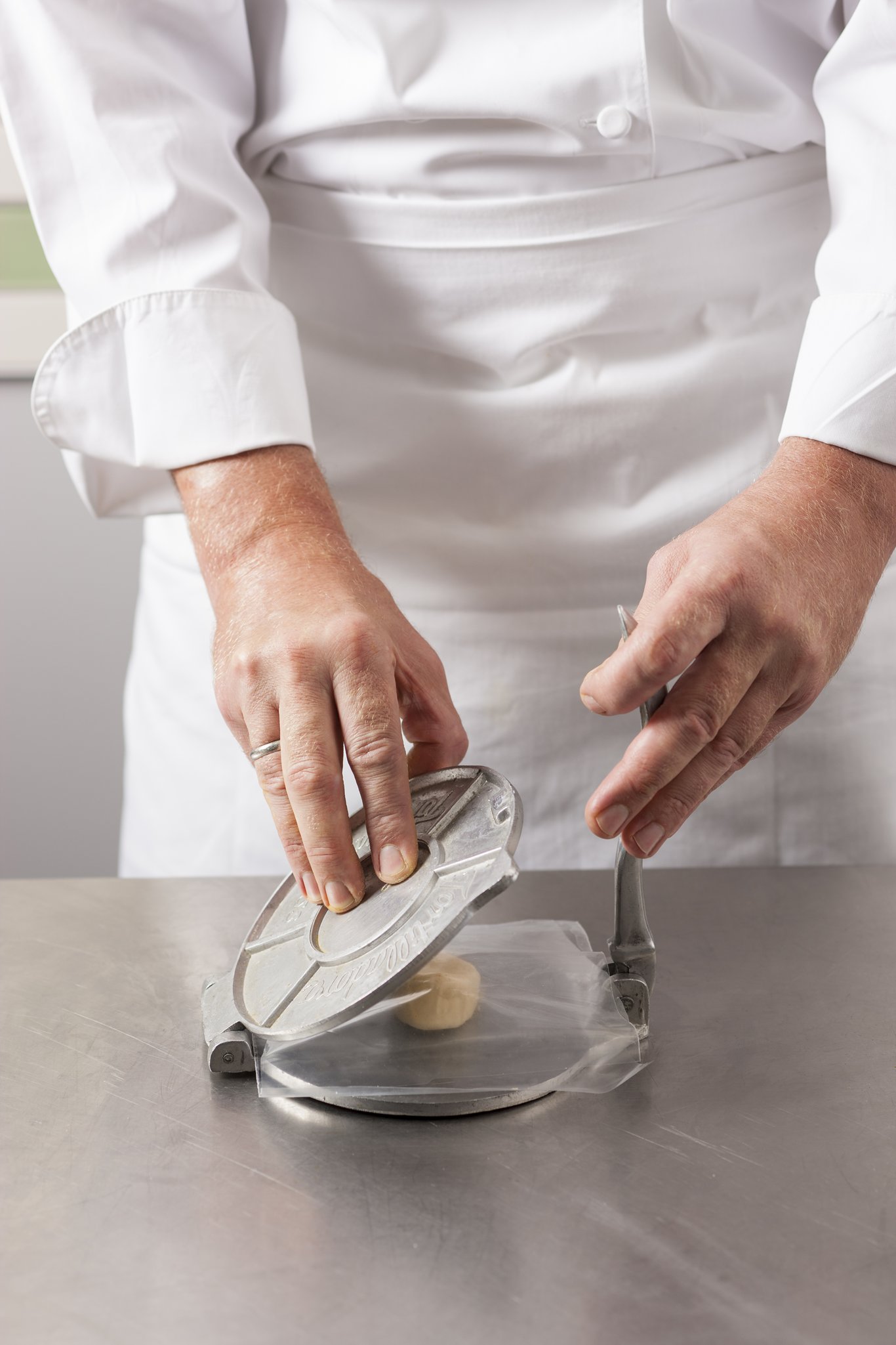 Pressing tortilla dough in a tortilla press.