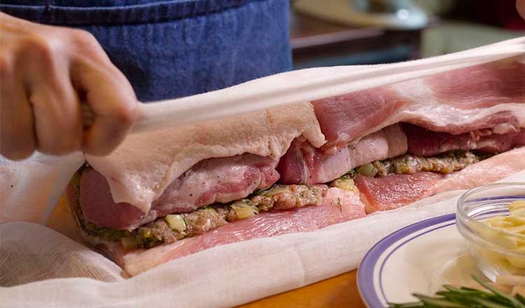 Porchetta being wrapped with cheese clothe