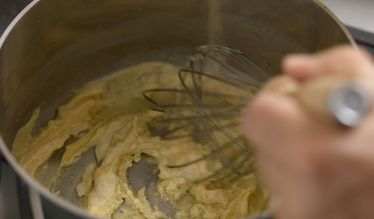 Whisking cooking roux in pot.