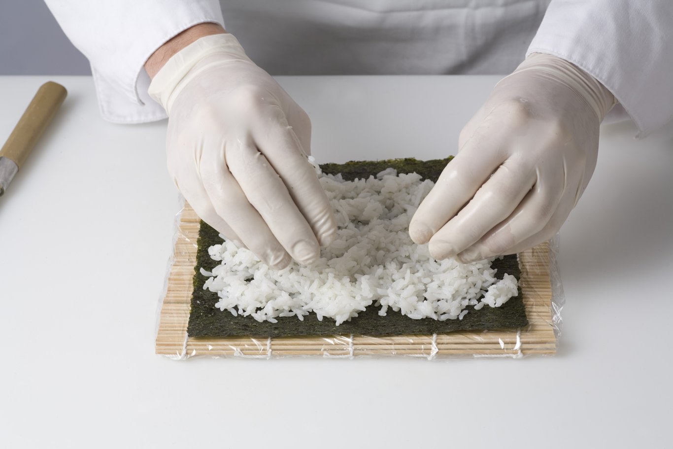 Spreading sushi rice on sheet or nori