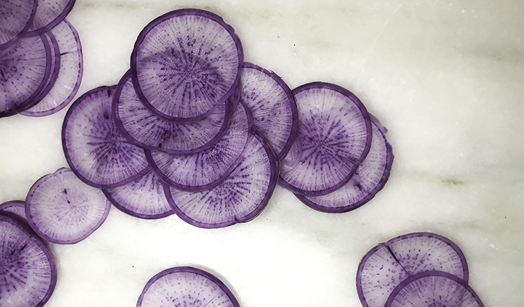 Thinly sliced purple radishes on marble