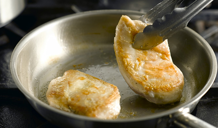 Turning sauteed chicken in a pan