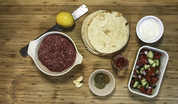 Ingredients for crispy lamb pitas, including lamb, yogurt, lemon, garlic, herbs, vegetables, and yogurt.