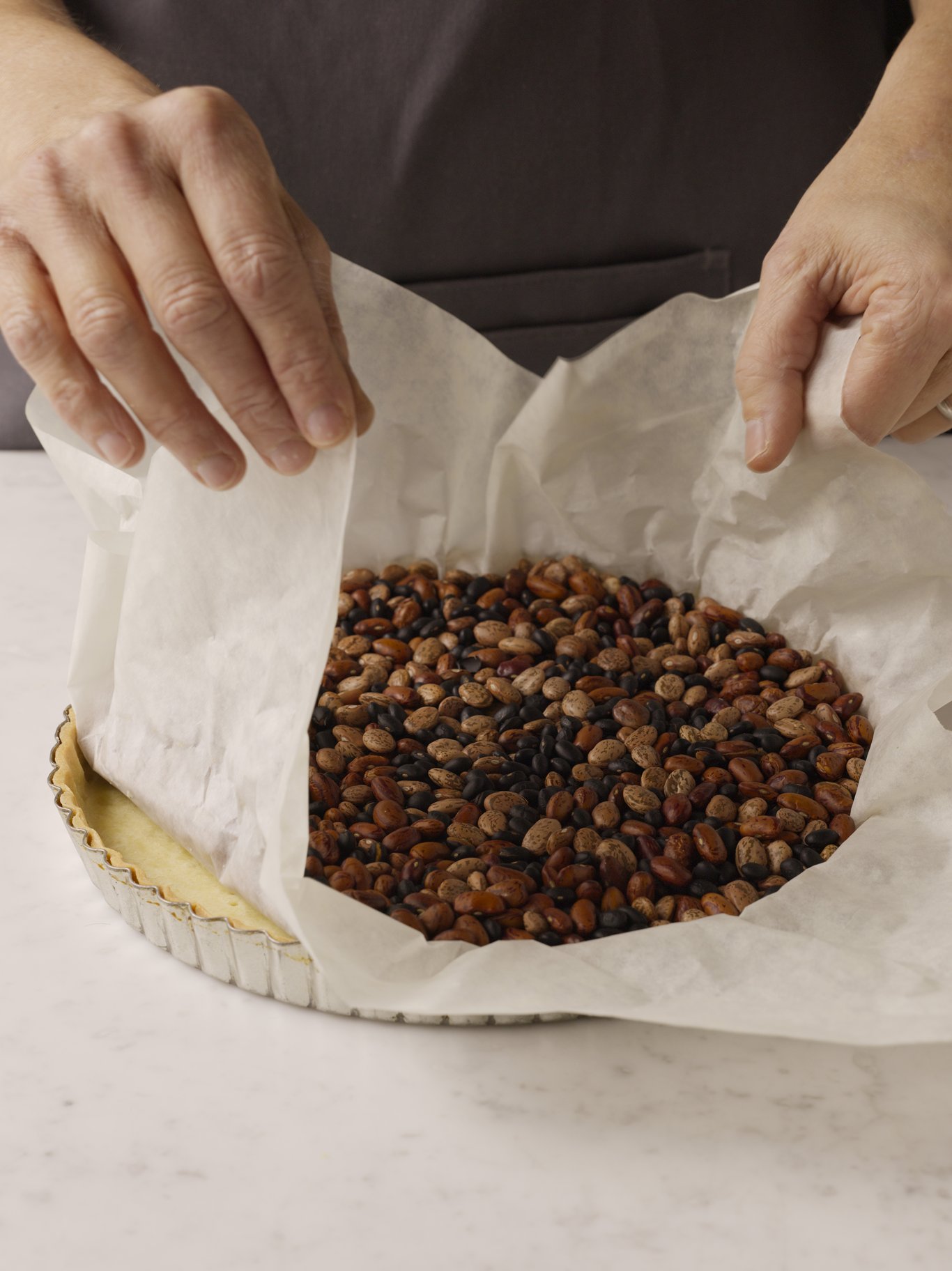 Removing pie beans from a baked tart shell.