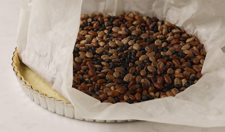 Removing pie beans from a baked tart shell.