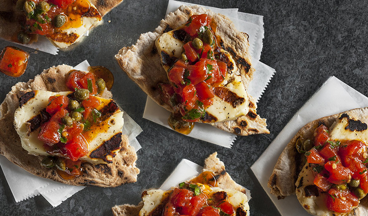 Grilled east mediterranean cheese on a pita bread topped with tomatoes and capers