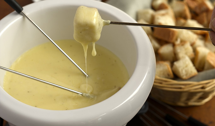 A traditional Swiss fondue, served with bread cubes, cornichons, and pearl onions.