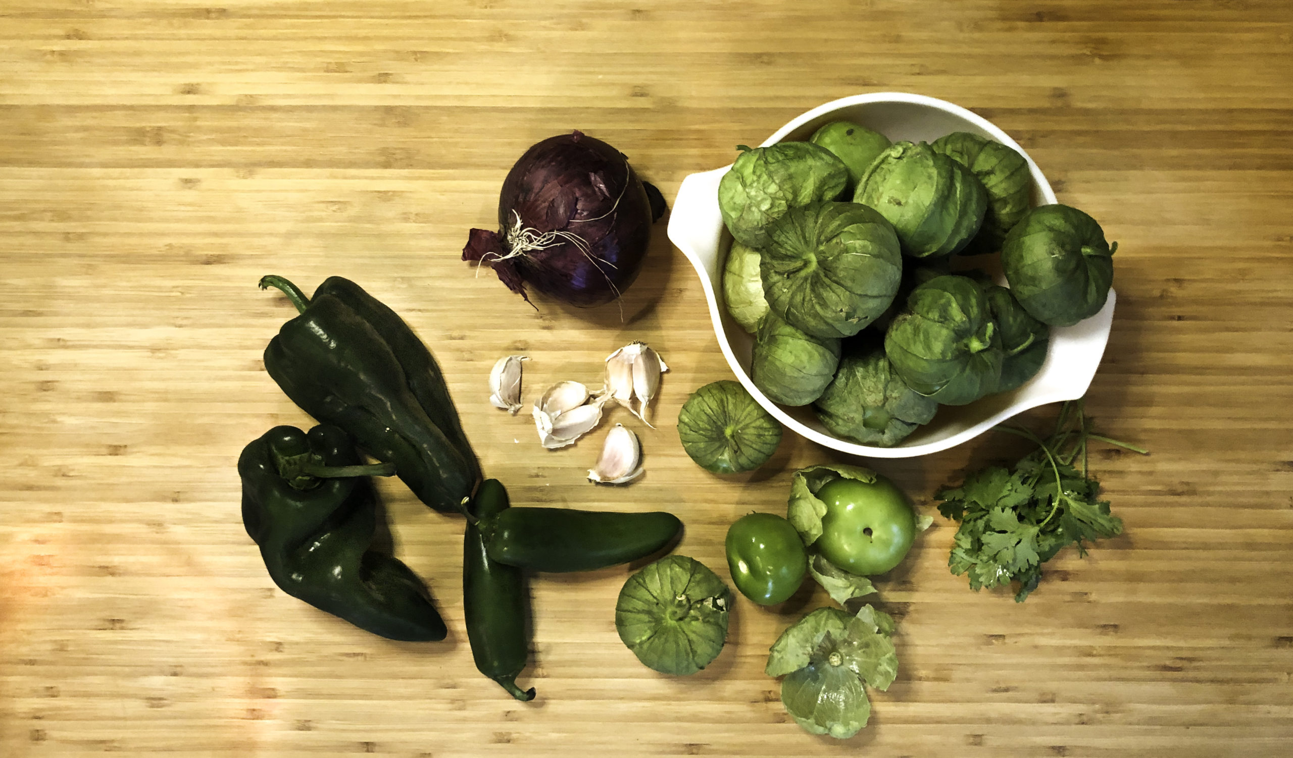 Ingredients for roasted salsa verde: Poblanos, jalapeños, tomatillos, garlic, cilantro, red onion