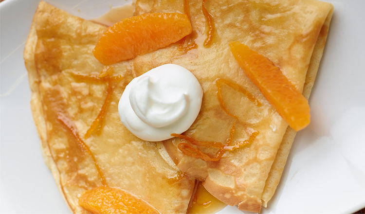 Crepes Suzette with whipped cream and orange segments