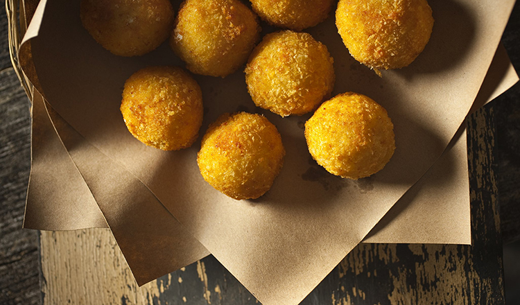 Breaded Risotto Fritters stuffed with Mozzarella and Sausage and served on brown paper