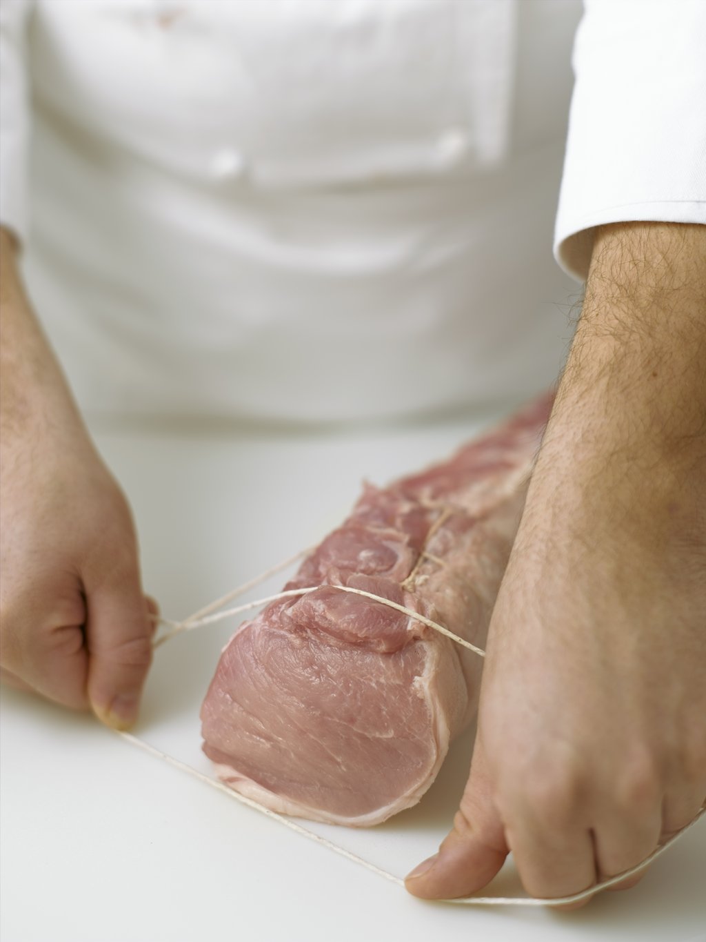 Step three: Continue to enlarge the loop until it is wide enough to pass easily around the thicker end of the meat, completely encircling it.