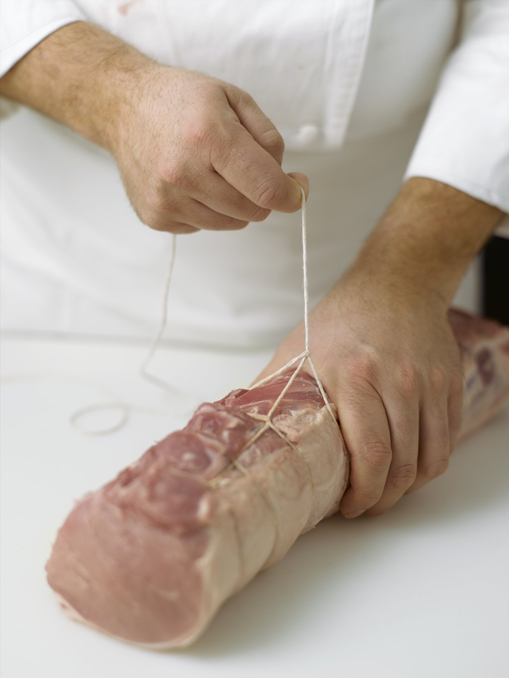 Step five: Pull the loose end of the string until the loop is securely tightened around the meat.