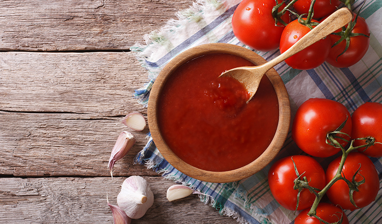 tomato ketchup with garlic and basil in a wooden bowl. horizontal view from above