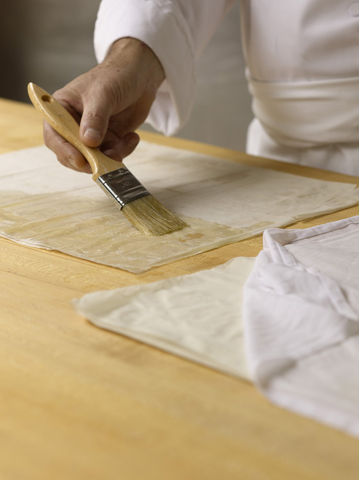 Brushing layers of phyllo dough with butter.