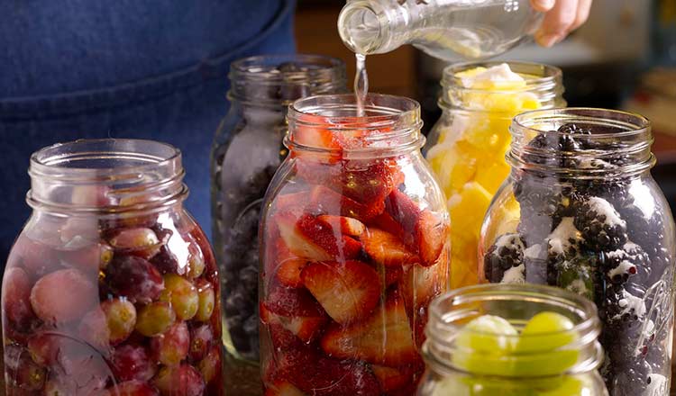 Pouring grappa into berry-filled jars