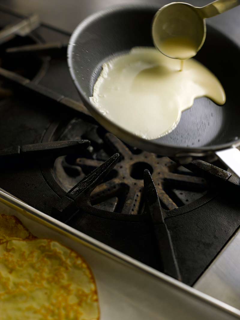 Adding crepe batter to a pan