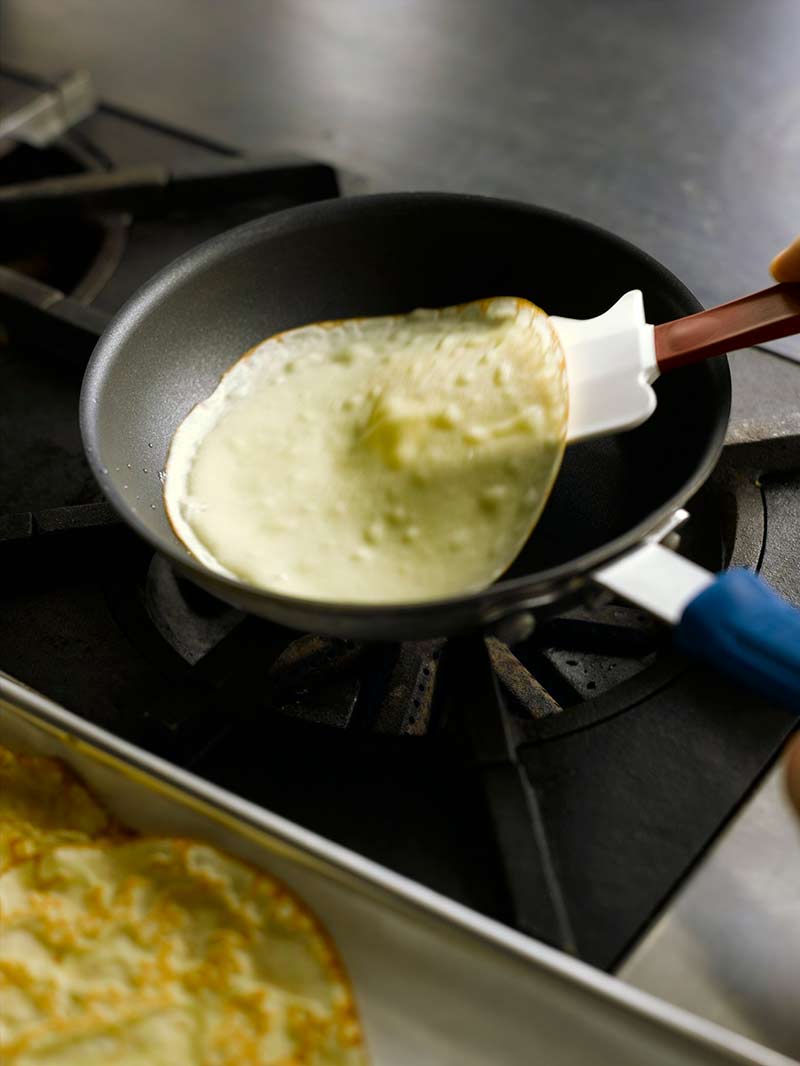 Using a silicone spatula to release the crepe from the pan