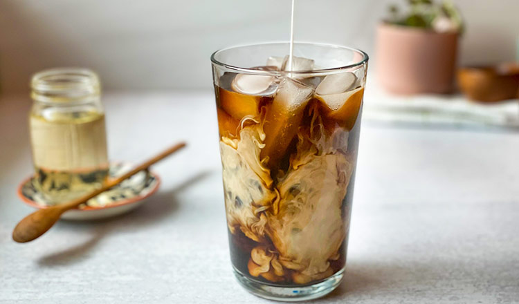 Cream being added to cold brew coffee with ice