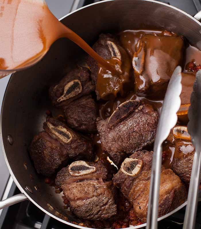 Adding liquid to a pot of short ribs