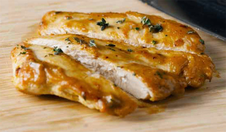 Chicken with almond and orange dressing, sliced on a cutting board