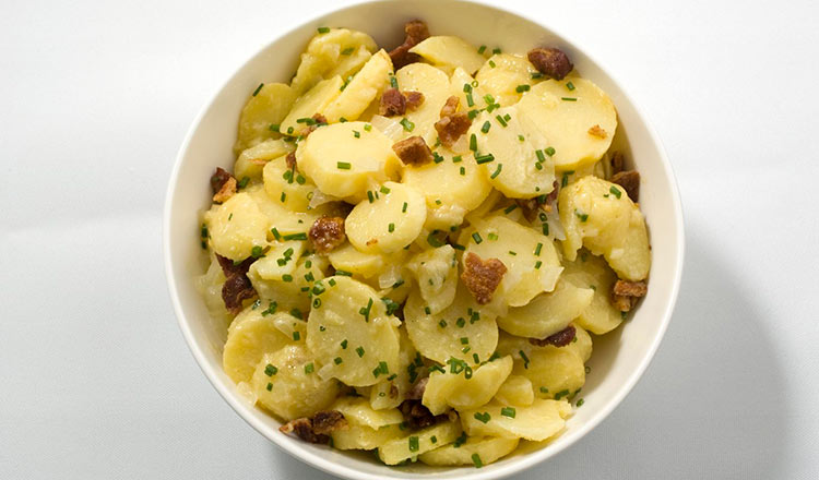 Sliced potatoes in a bowl with bacon