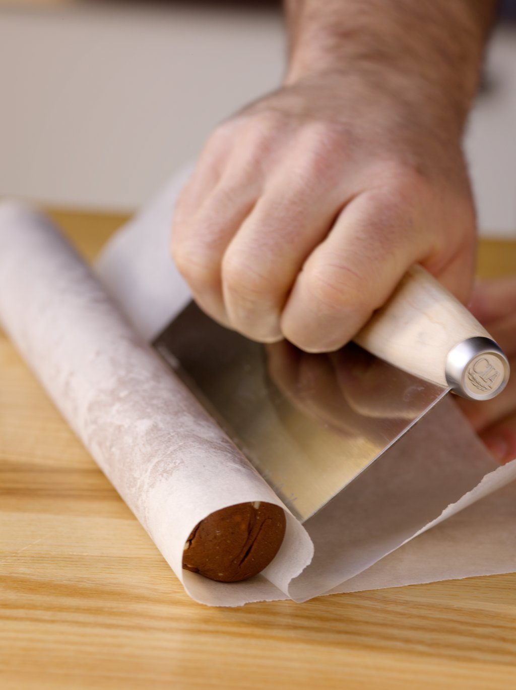 Place a log of icebox cookie dough on a piece of parchment paper and use a bench knife to wrap the log tightly in the paper. The log can now be chilled or frozen until you are ready to bake.