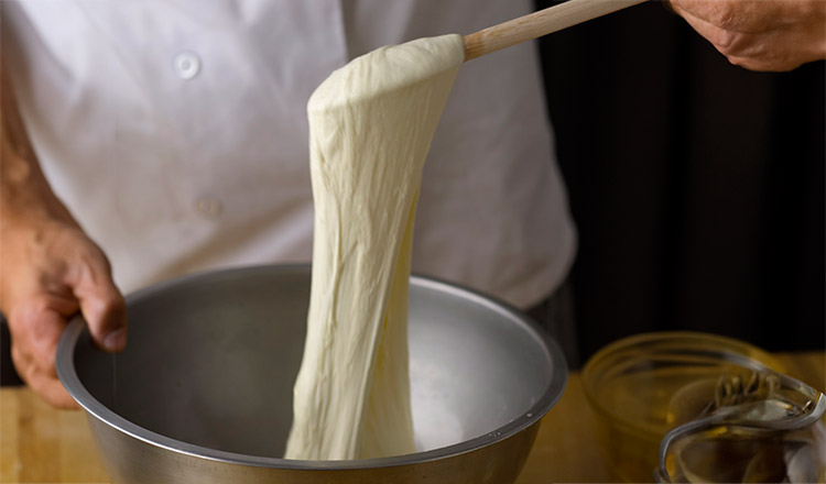 stretching fresh mozzarella cheese from a bowl