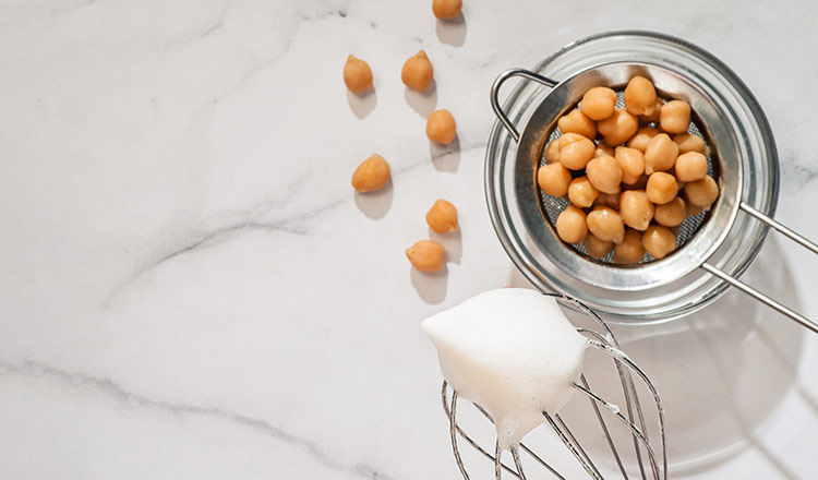 Chickpeas draining with a whisk of whipped aquafaba