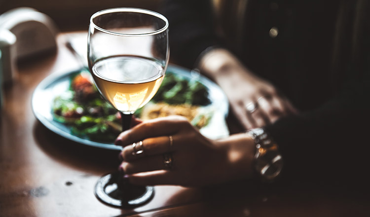 female hand with glass of wine and food
