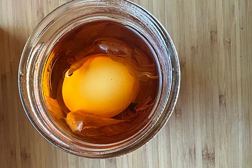 An egg soaking in onion skin dye