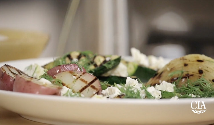 Drizzling oil over a plate of grilled vegetables