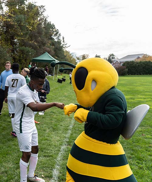 Bee mascot fist-bumping a soccer player