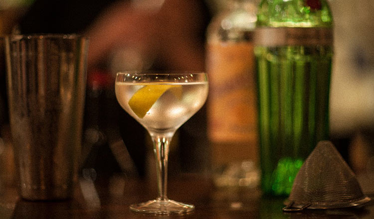 A gin martini with a lemon twist on a bartop