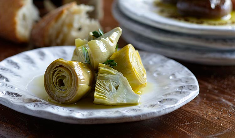 Combine the wine, vinegar, allspice berries, salt, bay leaves, and garlic in a large, nonreactive pan (stainless steel or enameled cast iron are best; no aluminum, please) and simmer on low Add the artichokes and continue to simmer for 5 minutes. The artichokes should be completely submerged; if they are floating above the surface, put a small plate or saucer on top of them to keep them under the surface. Lift the artichokes from the cooking liquid with a slotted spoon and let them drain upside down on several layers of paper towels. When they are completely cool place them in one or more glass jars (choose jars with good lids) and add the parsley and marjoram. Pour in enough olive oil to cover the artichokes completely. Cover the jars and let the artichokes marinate at least 24 hours and up to 1 week in the refrigerator before serving them.