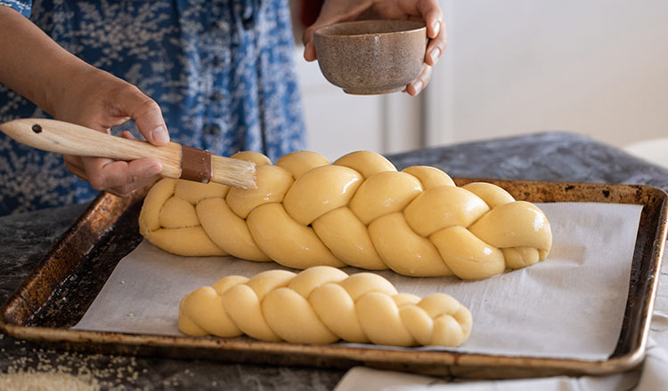 Brushing eggwash on braided challah dough