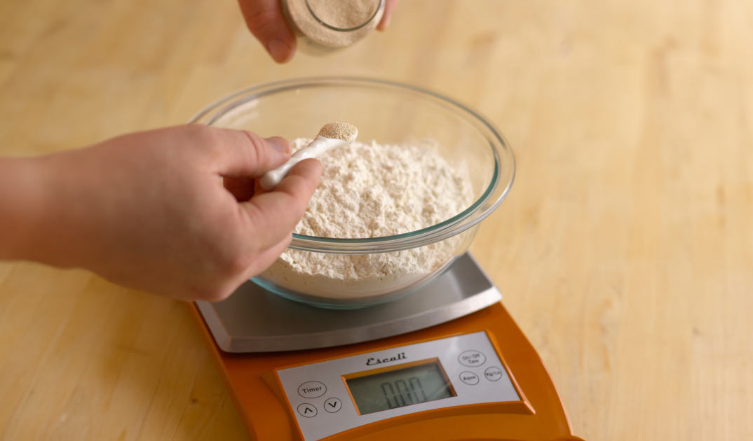 Weighing flour on an orange-colored digital food scale.