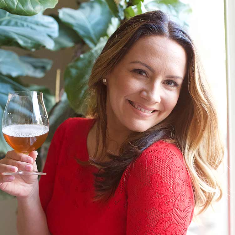 Anne Becerra Image of Anne Becerra holding a glass of beer.